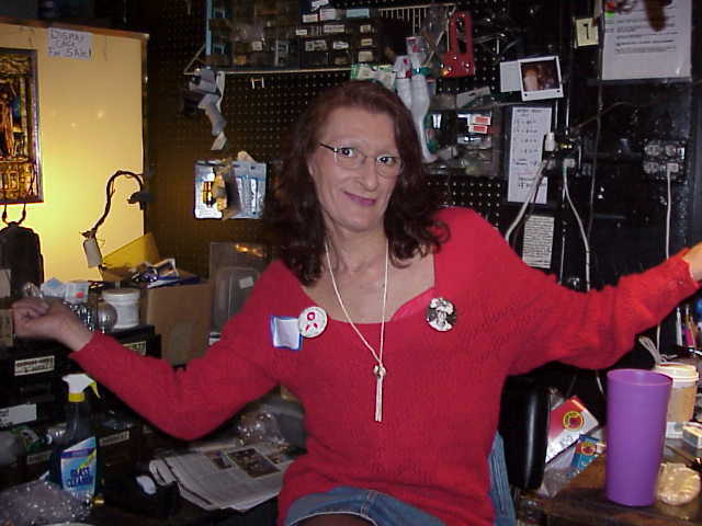 Download the full-sized image of A Photograph of Sylvia Rivera Posing with Her Arms Out, Wearing a Red Shirt and Denim Skirt