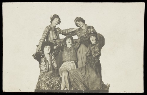 Download the full-sized image of Russian soldiers in drag, posing very close together, in front of a plain background. Photographic postcard, 191-.