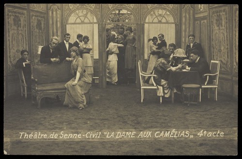 Download the full-sized image of French or Belgian prisoners of war, some in drag, posing on stage during a crowded scene of "La dame aux camélias"; at Sennelager prisoner of war camp in Germany. Photographic postcard, 191-.