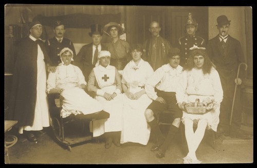 Download the full-sized image of Amateur actors, some in drag, pose for a group portrait. Photographic postcard, 191-.